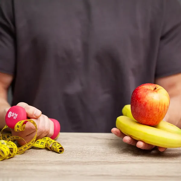 weightloss hypnosis image of a man holding a dumbbell, apple, banana, and measure